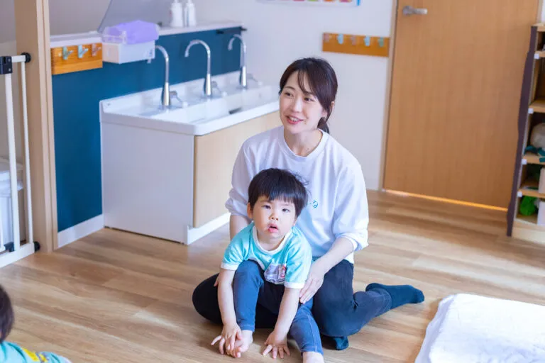 子供を抱っこして床に座る女性の写真