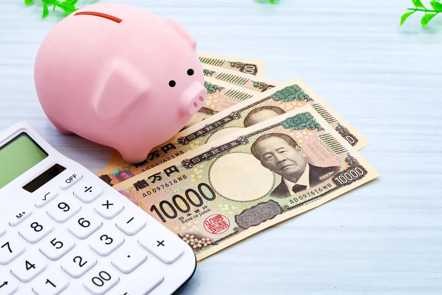貯金箱とお金、電卓の写真